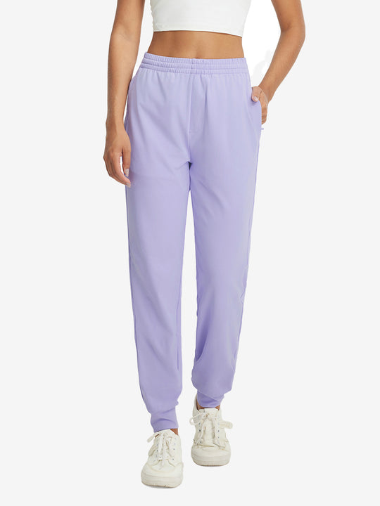 Model with hand in pocket wearing lightweight women's stretchy joggers sweatpants in lavender purple.