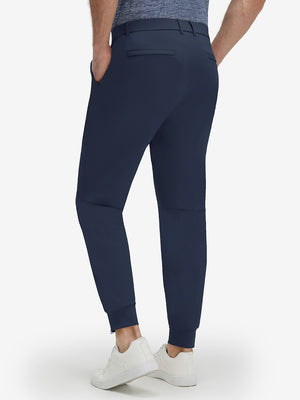 Back lower body shot of model wearing navy flat front golf joggers pants with belt loops