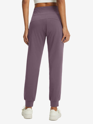 Model wearing women's stretch fleece lined water resistant joggers in light pinkish purple, showing the back lower body view.