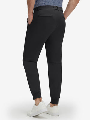 Back lower body shot of model wearing black flat front golf joggers pants with belt loops