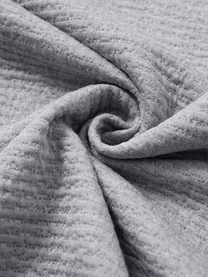 Close-up of fabric on textured insulated winter jacket, showing texture and finish in light grey heather.