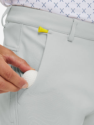 Hand placing a phone into front pocket of lightweight moisture wicking dress pants in silver grey.