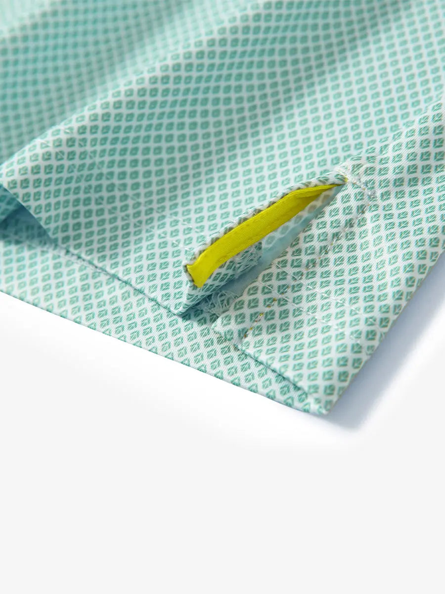Detail view of the green plant pattern polo, focusing on the neatly finished hem opening and fresh design.