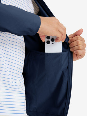 Hand placing iPhone into inner pocket of lightweight water-resistant outerwear jacket in blue indigo