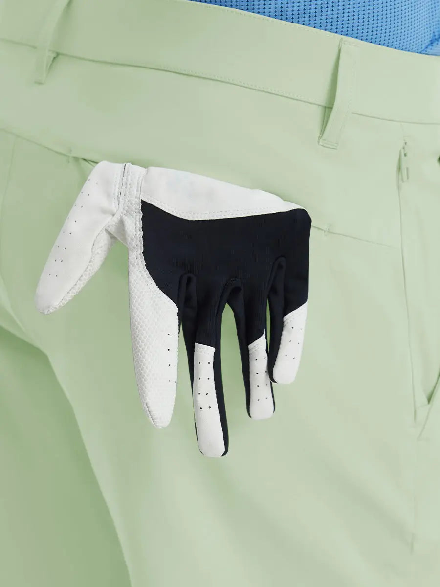 Back view of Player Fit Versatile Solid Shorts 9 Inch with golf glove tucked into right pocket – LIGHT GREEN