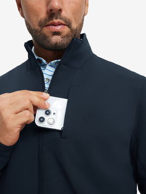 Close detail of hand in chest pocket of water-resistant zip up golf jacket in navy.