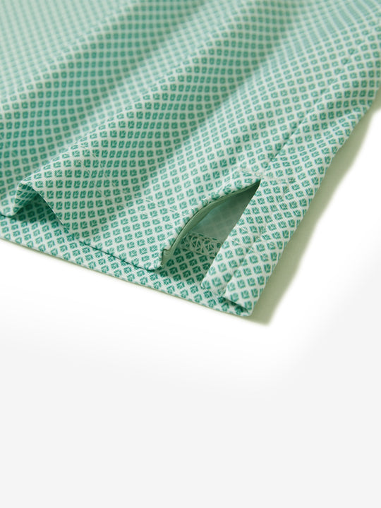 Hem slit detail of the green plant lightweight print long sleeve polo, showing fine stitching and finish.