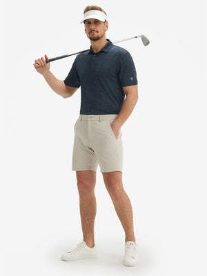 Full-body shot of model holding a golf club in navy coconut tree breathable jacquard pattern 3-button golf polo
