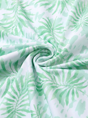 Close-up of light green leaf performance jersey print polo fabric showing breathable texture.