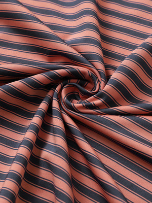 Close-up of orange dark blue yarn dyed stripe polo fabric showing distinct woven stripes and textured surface.