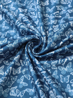 Close-up of blue white butterfly performance jersey print polo fabric showing breathable texture and vibrant pattern details.